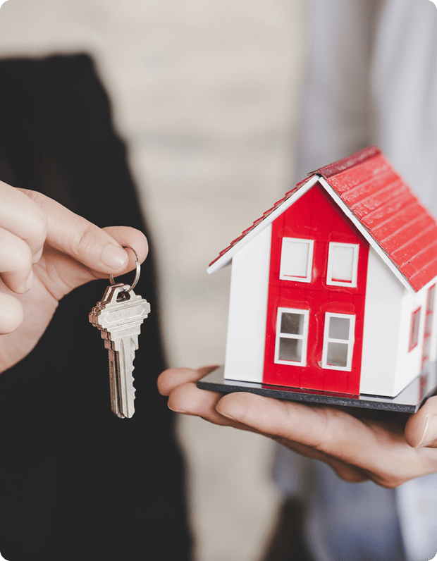 Hand holding a model house with keys