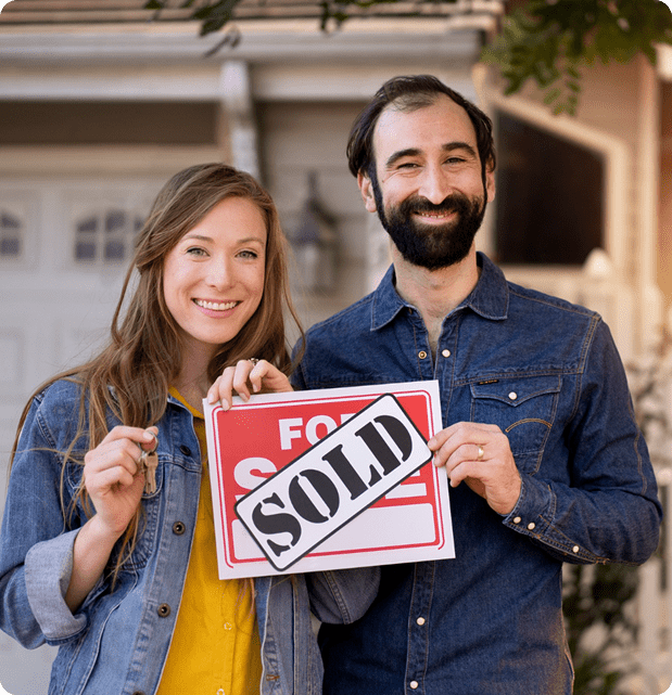 Homeowners holding a sold sign after selling their house