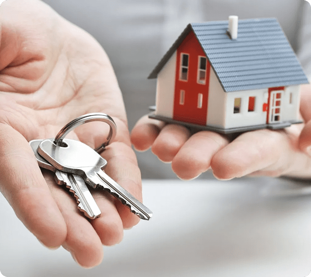 Hand holding house keys and a model home